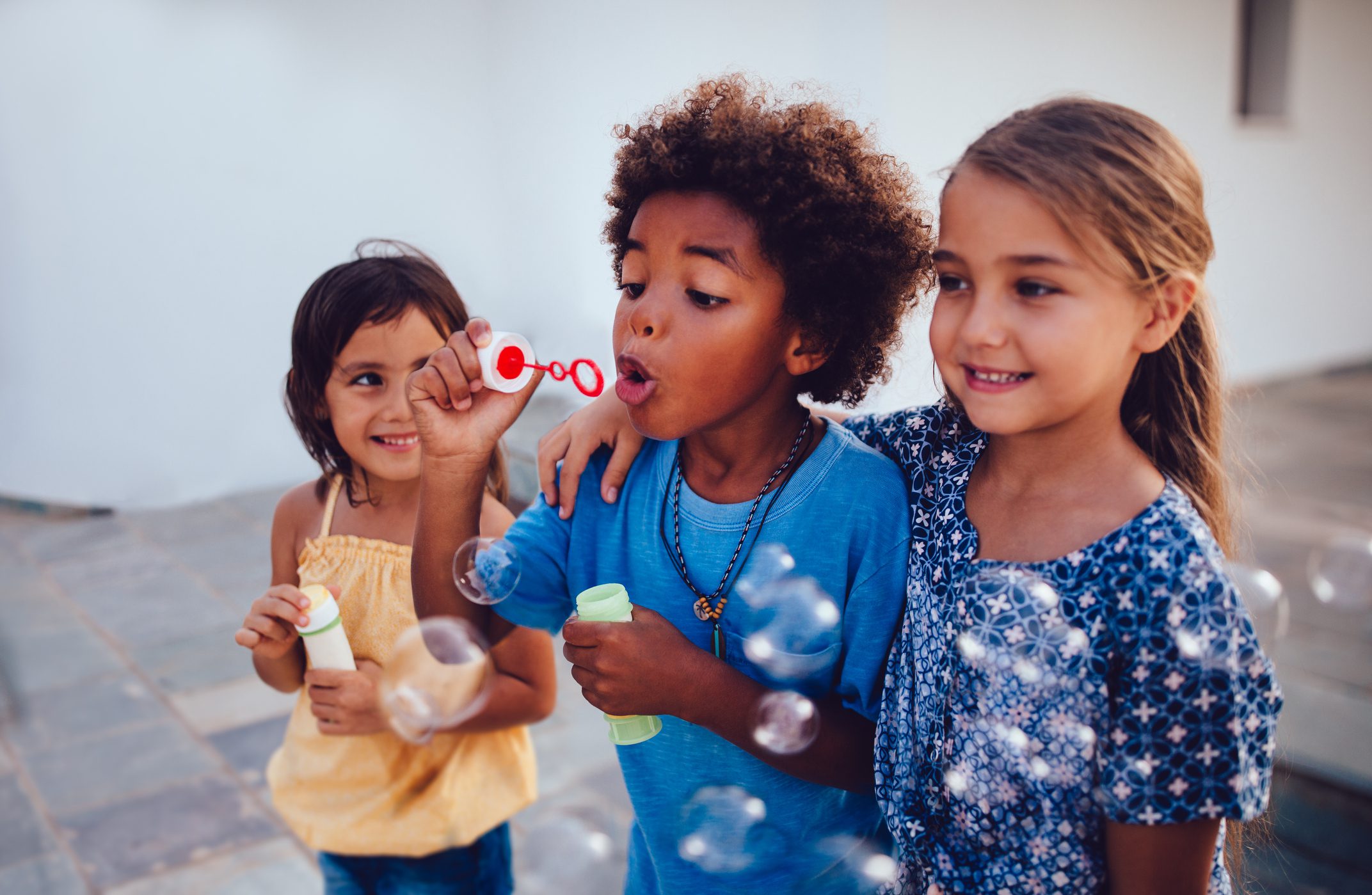 Group of happy children outside playing and blowing bubbles.