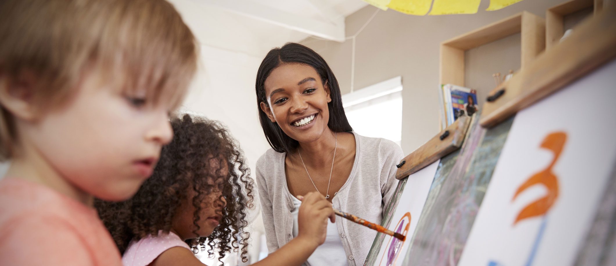 Teacher helping students with a painting project at a learning center.
